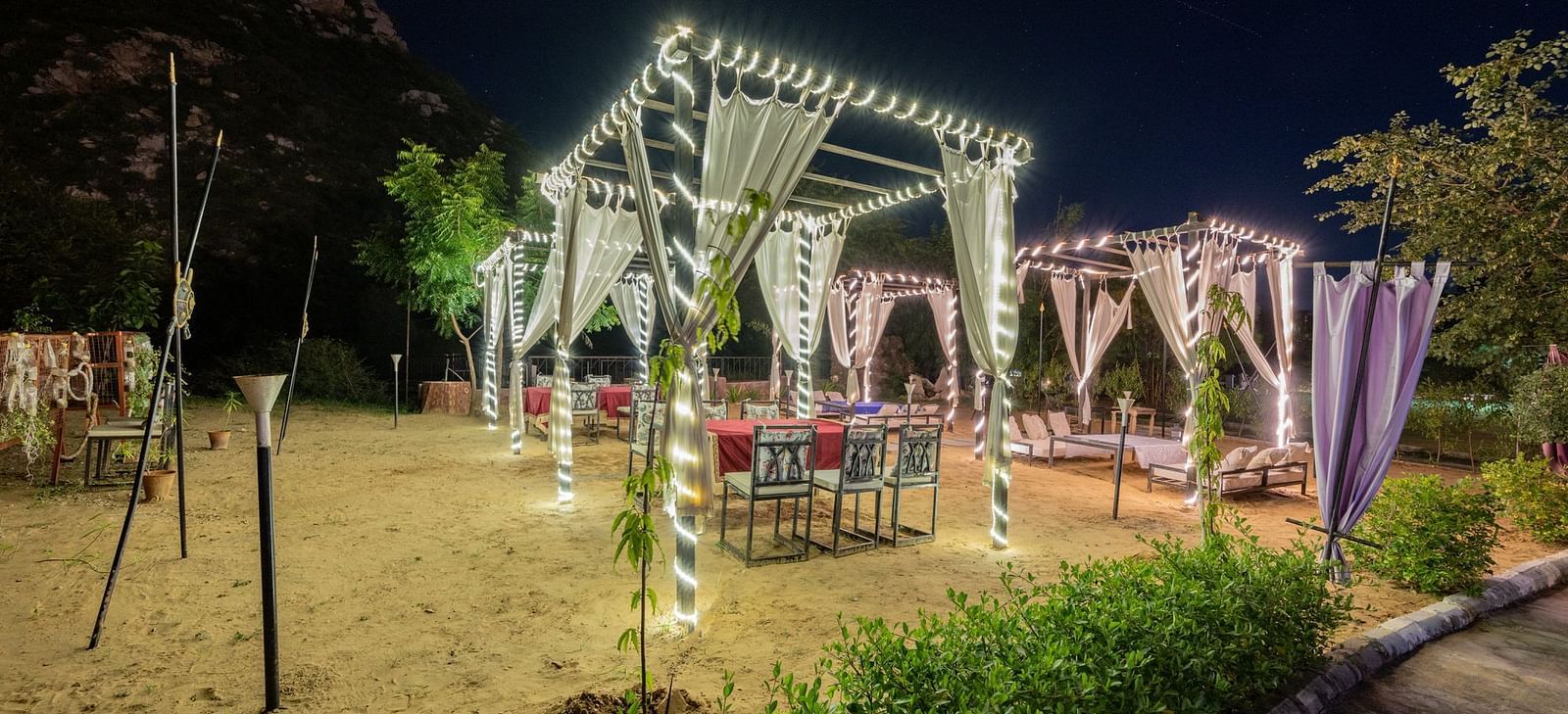 Night view of an open dining space decorated with sheer curtains and lights at Valley by Grassfield.
