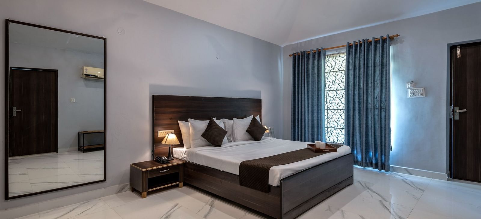 Side view of a room with a bed and a large mirror beside it at Valley by Grassfield.