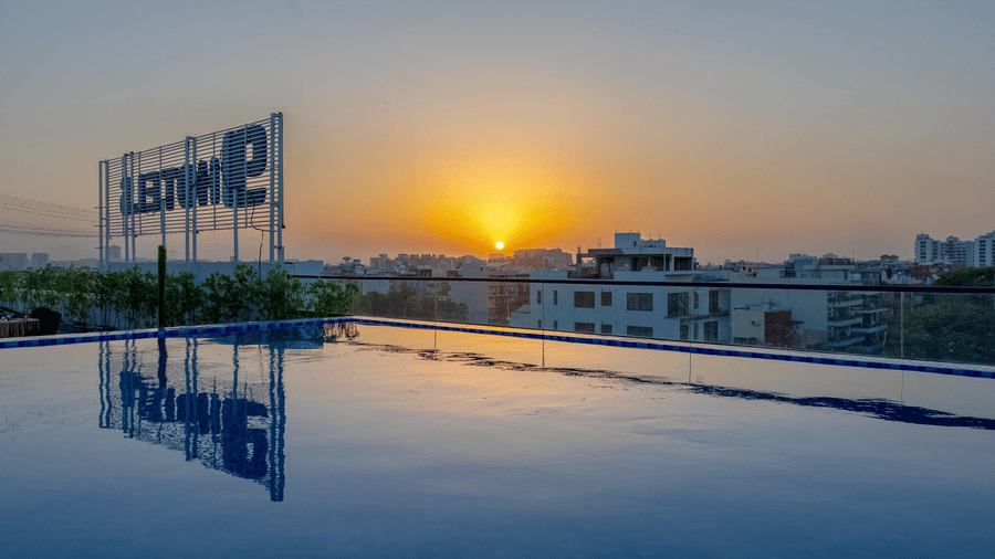 A close up of the rooftop swimming pool featuring calm waters mirroring the sunset skies at Hotel 91 Privé, Gurugram.