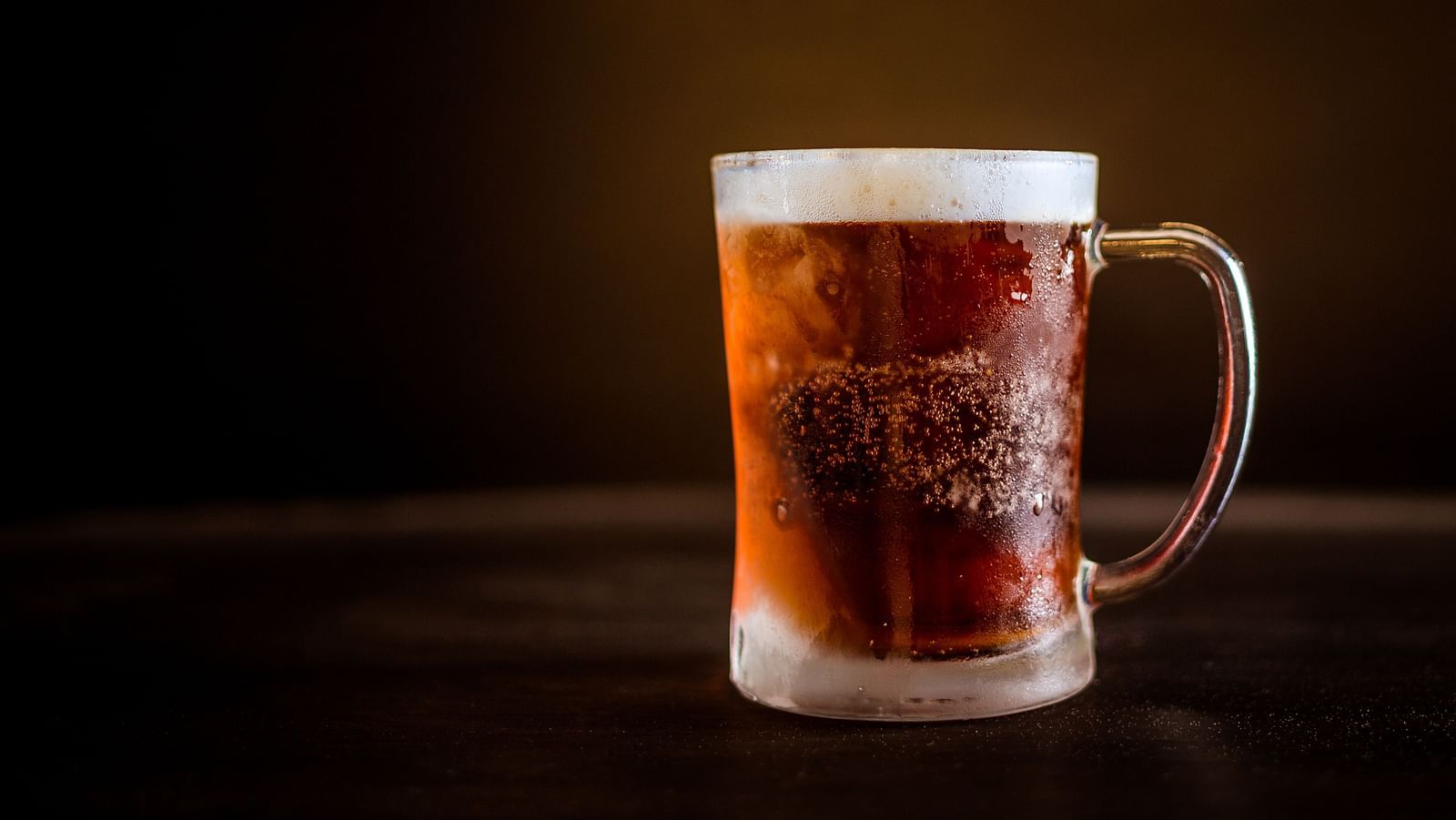 a mug of craft beer placed on a table with dark background