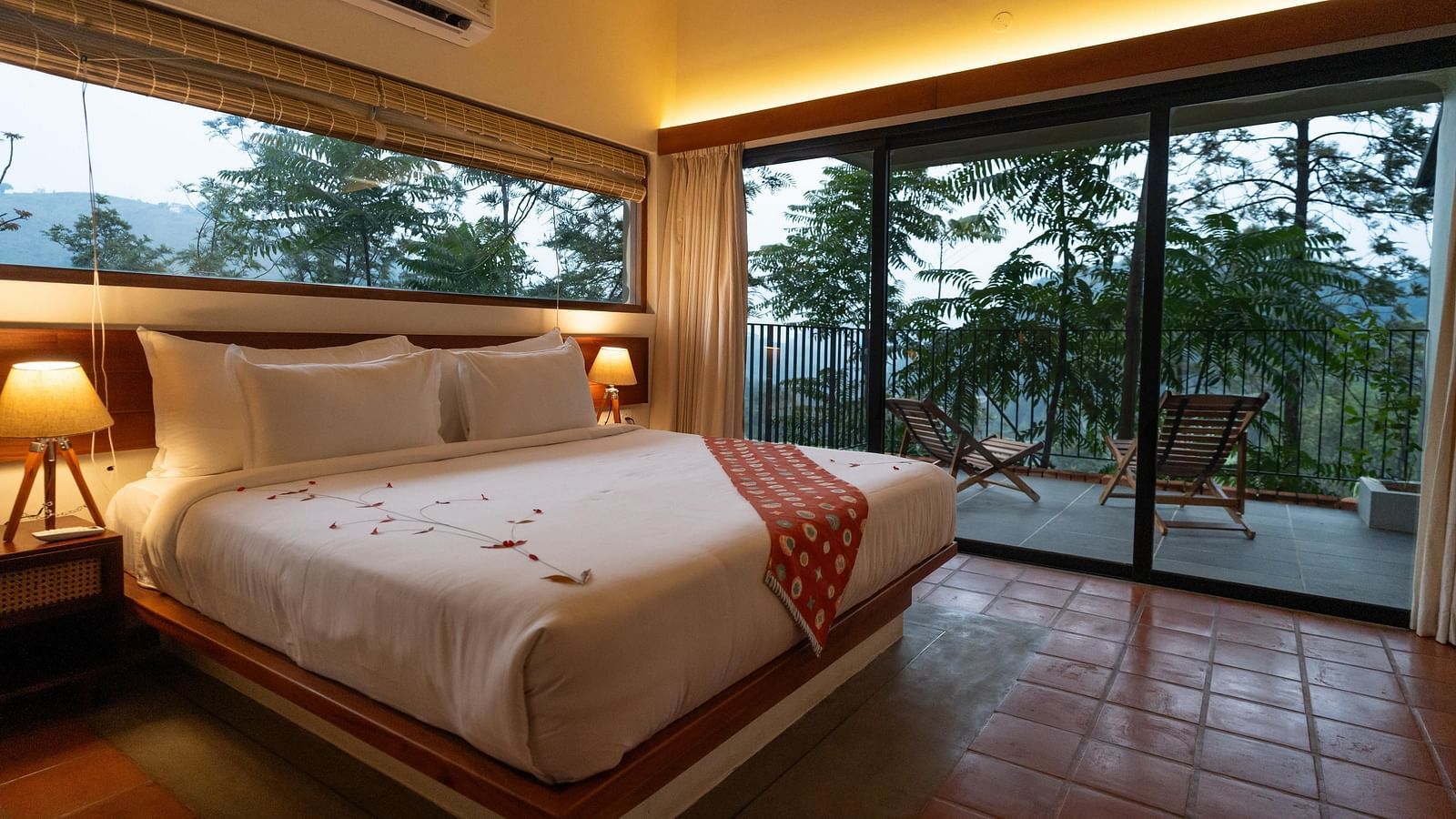  A well-appointed bedroom at Vaasta Vagamon featuring a large bed with a decorative runner, and expansive windows overlooking a scenic view.