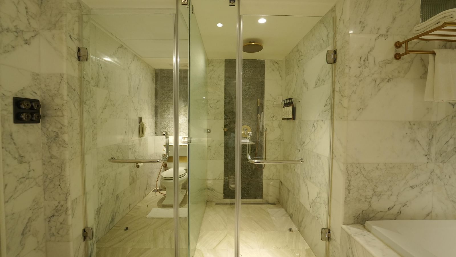 A white marble bathroom at Fragrant Nature Cochin with a separate glass-enclosed shower and toilet.
