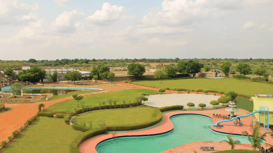 Swimming pool and party lawn surrounded by the garden at The Palm Resort, Bhilwara