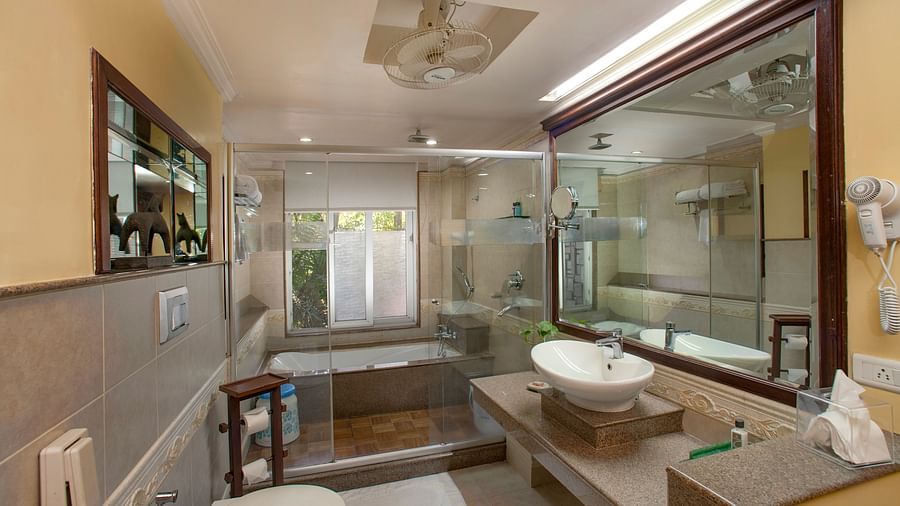 the bathtub enclosed inside a glass closet and a wash basin outside it - Mayfair Spa Resort & Casino Gangtok 