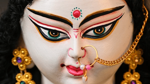 A close-up of a deity's face, adorned with jewelry, displaying a serene expression.