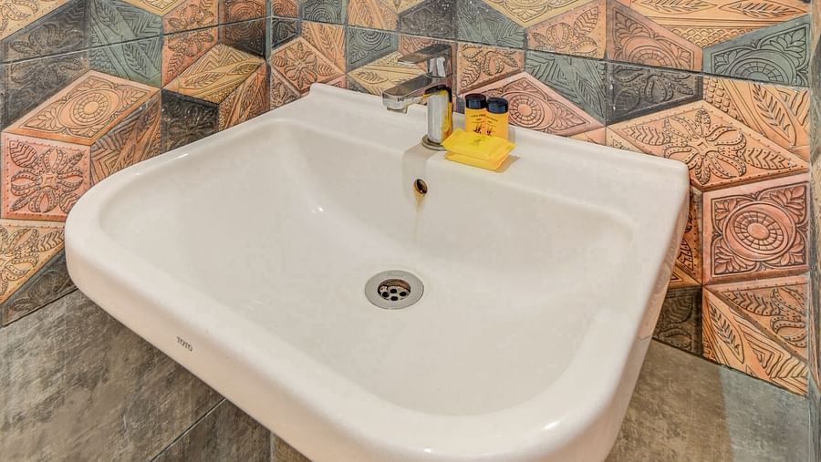 A wash basin with a wall-mounted mirror above it at Hari Govinda’s JN Stay, Shakthinagar