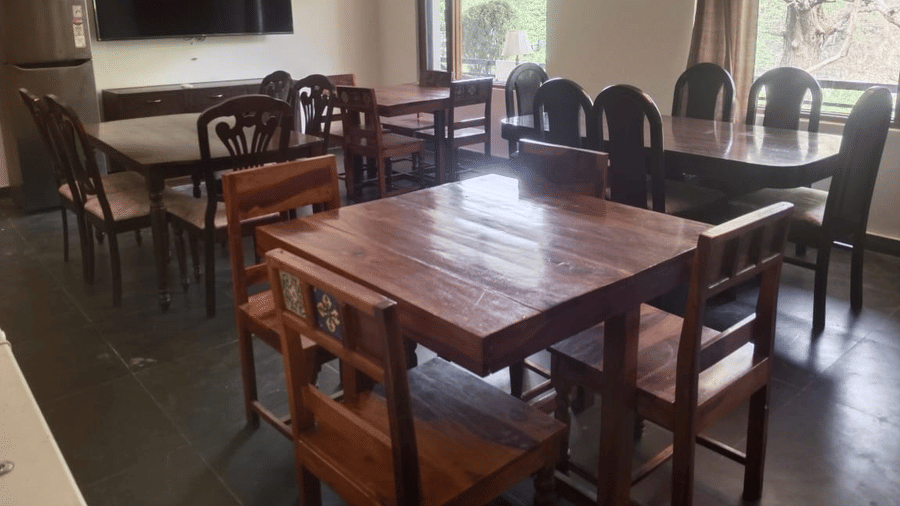 Dining area with wooden tables and chairs, large windows and natural light.