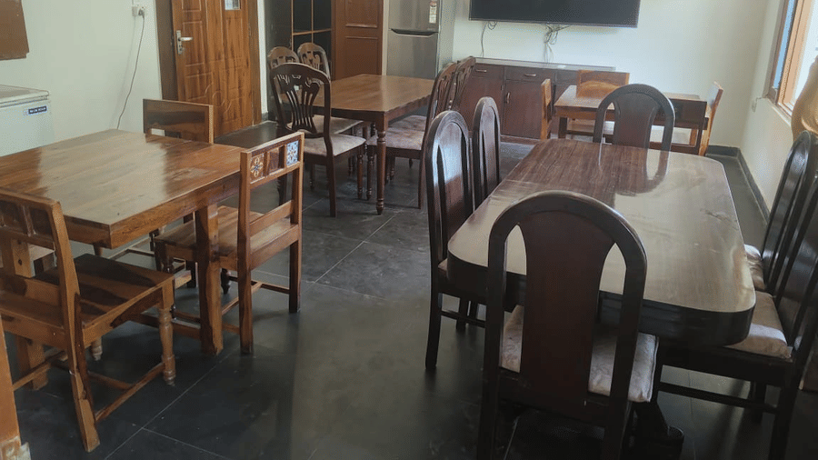 Dining area with wooden tables and chairs, a wall mounted television and comfortable indoor seating.