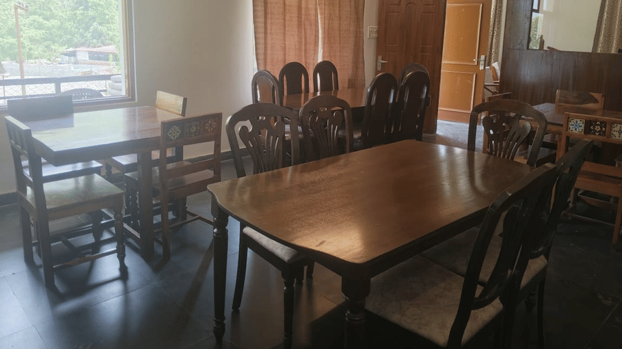Indoor dining area with wooden tables and chairs, large windows and curtains.