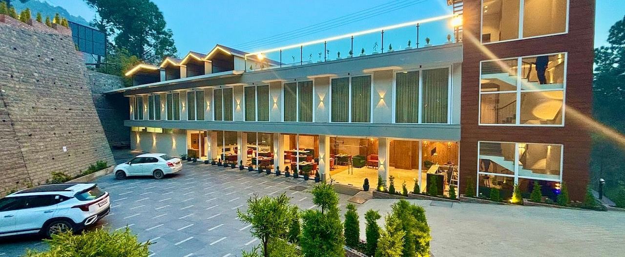 Exterior view of the ARNISA Boutique Hotel building with glass facade and neatly landscaped driveway