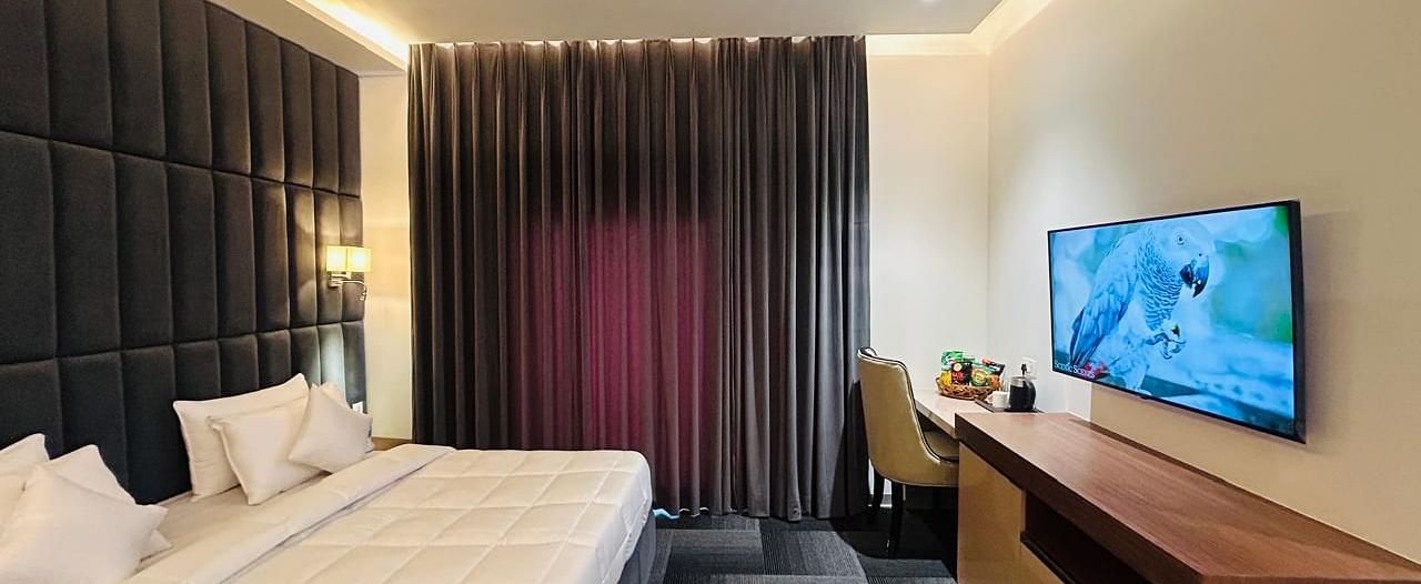 full view image of the executive room with a plush double bed and a wall mounted television at Eminence The Corbett