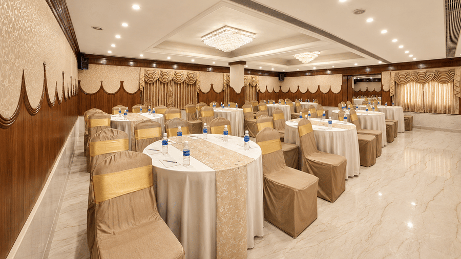 A hall with multiple chairs, chandeliers, and a stage at Raj Park, Chennai.