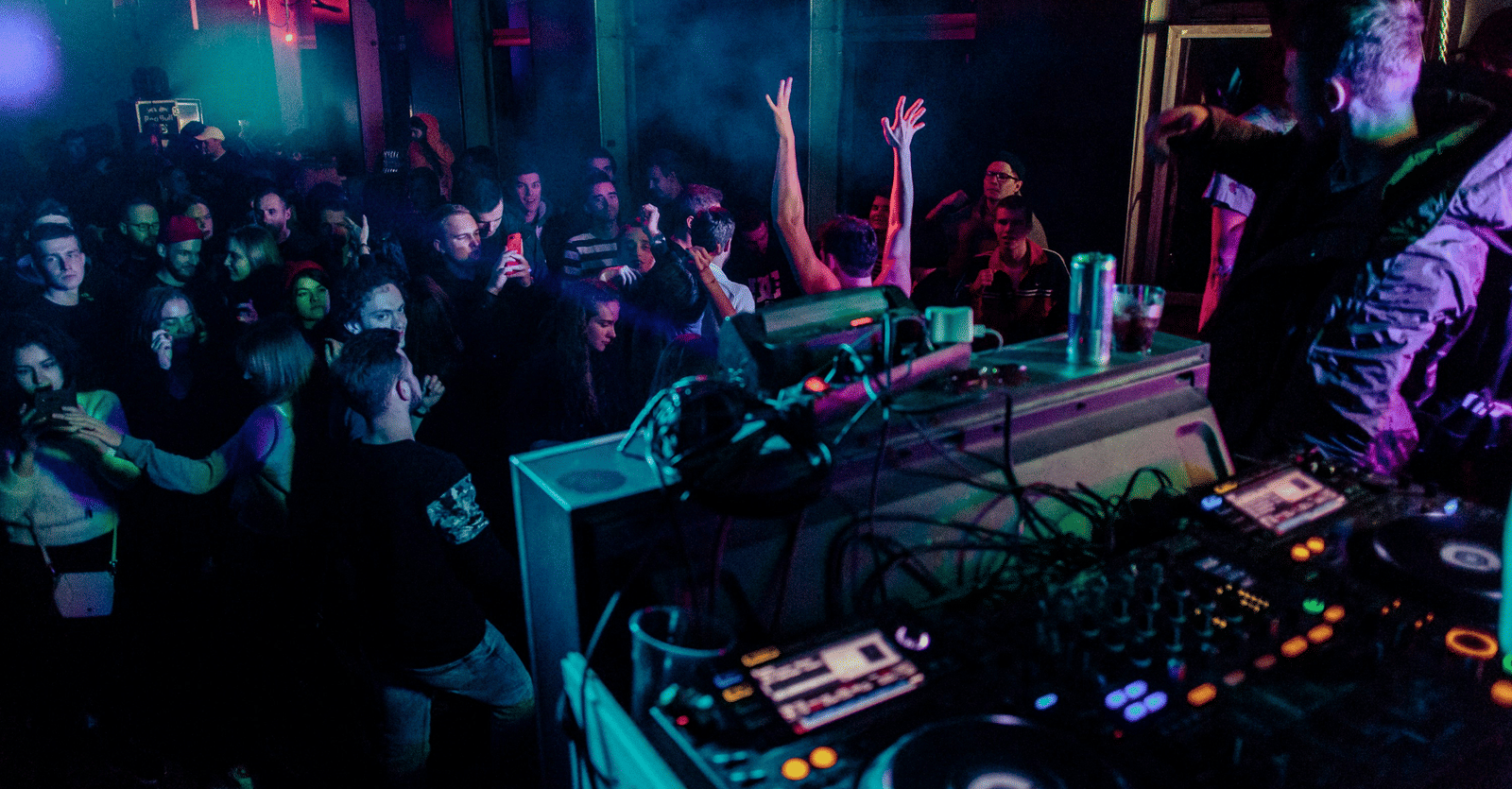 A view from the stage of a DJ playing music to a crowd of people. who are dancing - Nightlife in Pondicherry