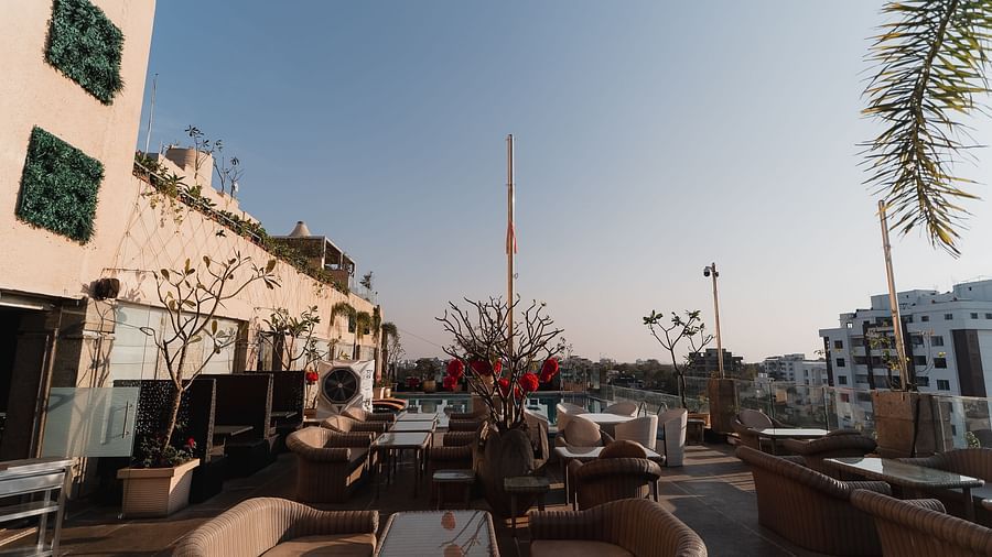 An outdoor dining setup at Hotel Ashok Nagpur with cushioned chairs around tables.