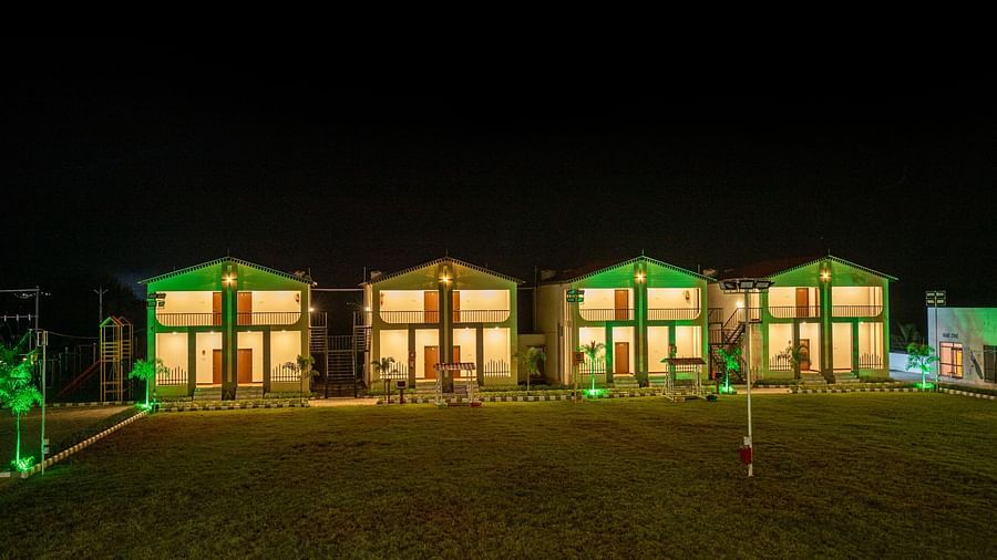  The resort buildings glowing in green lighting, set against a clear blue sky, highlighting the architectural beauty - VITS Select Diamond Resort, Sasan Gir
