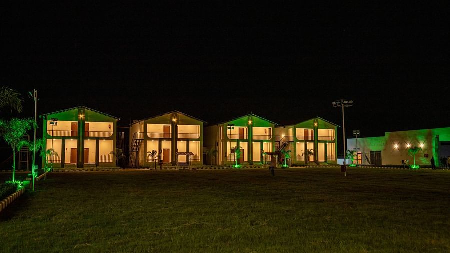  A view of the resort's exterior at night, with green lights accentuating the building’s design and a well-kept lawn - VITS Select Diamond Resort, Sasan Gir