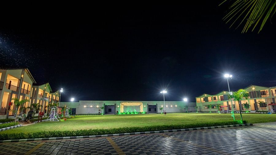  A wide-angle view of the resort at night, with buildings illuminated by green lighting and a paved pathway leading through the grounds - VITS Select Diamond Resort, Sasan Gir