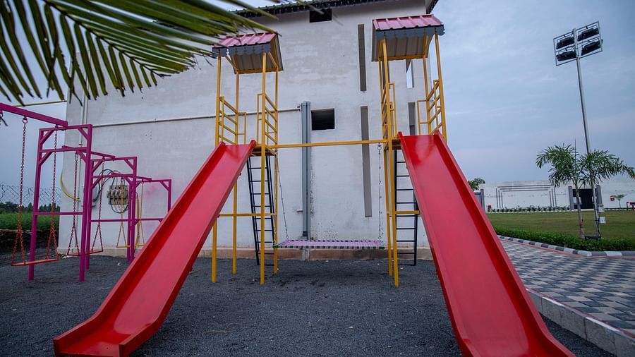 A playground featuring multiple red and yellow slides, framed by palm trees and green landscaping - VITS Select Diamond Resort, Sasan Gir