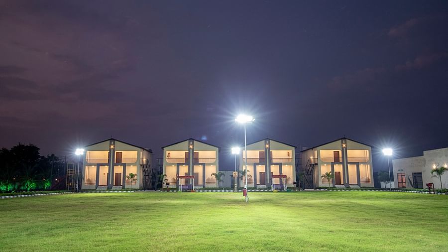 The resort’s outdoor area lit up at night, with bright lights illuminating the building and the surrounding lawn for a peaceful evening ambience - VITS Select Diamond Resort, Sasan Gir