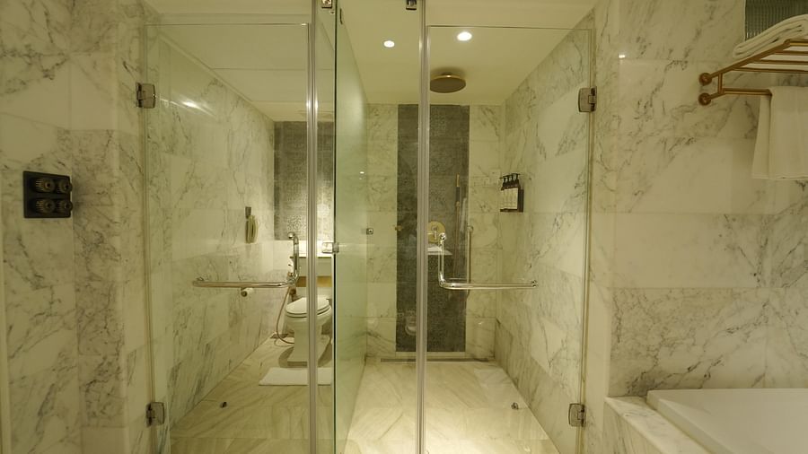 A white marble bathroom at Fragrant Nature Cochin with a separate glass-enclosed shower and toilet.