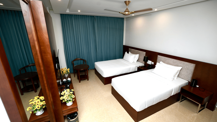 A modern Deluxe Twin Room in Le Royale Palace with neatly made twin beds, a ceiling fan, 