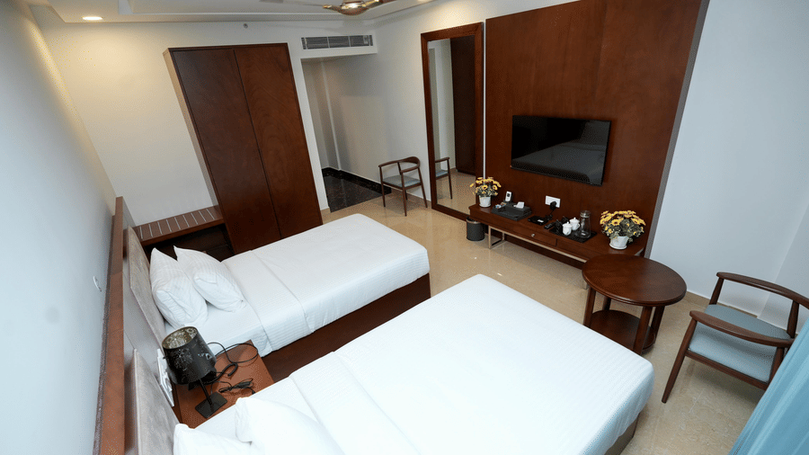 A side view of Deluxe Twin Room with neatly made twin bed, a wall mounted TV, and wooden furnishing