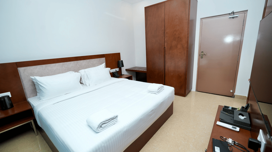 A Family Suite bedroom at Le Royale Palace featuring a king-size bed, wooden furnishings, and soft ambient lighting