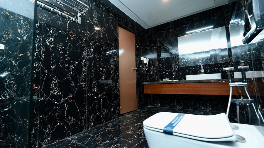 A Family Suite bathroom at Le Royale Palace showcasing a sleek black marble finish with premium fittings and a vanity counter