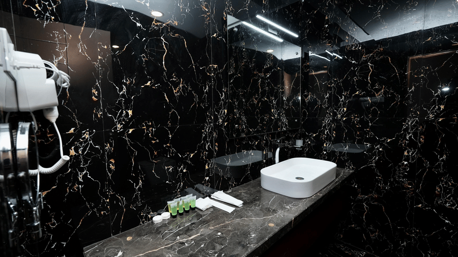 A Family Suite bathroom at Le Royale Palace featuring a polished black marble design with a vanity counter, sink, and essential toiletries