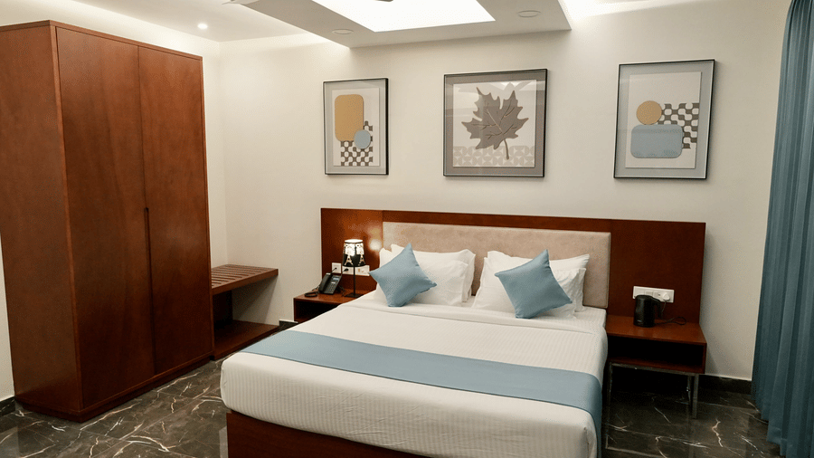 A bedroom in the Majestic Suite at Le Royale Palace featuring a king-size bed, wooden wardrobe, and framed wall art above the headboard