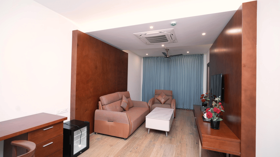A living area in the Majestic Suite at Le Royale Palace featuring plush armchairs, a work desk, and elegant wooden interiors