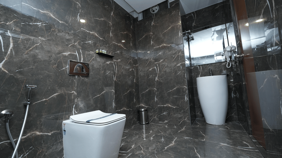 A luxurious bathroom in the Majestic Suite at Le Royale Palace with marble walls, modern fixtures, and a glass shower area