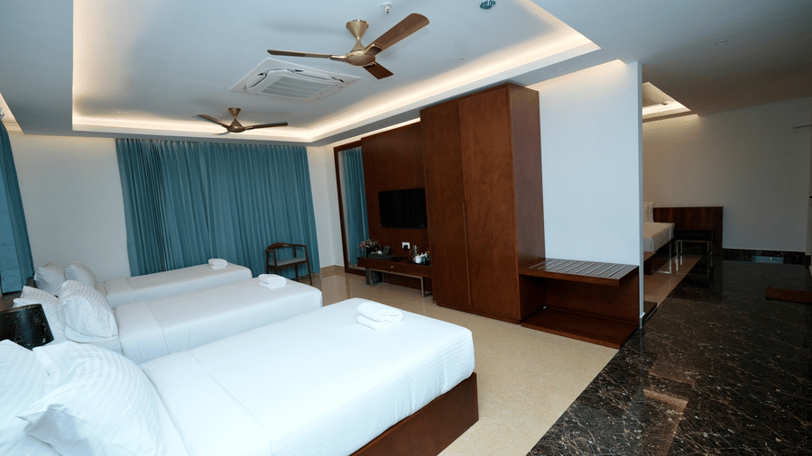 A bright Standard Family Deluxe Room at Le Royale Palace with a comfortable bed, draped curtains, and a work desk