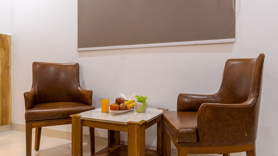 Seating space in the room at Hotel Corporate Suites featuring 2 chairs facing a coffee table with fruits on it