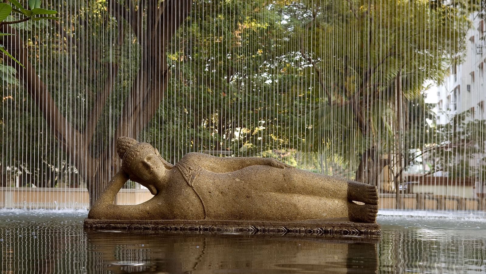 Bronze sculpture of a reclining figure with a water falling in front, creating a unique visual effect - The Raintree, St. Mary's Road.