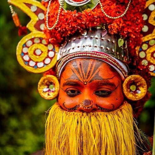 A man wearing the traditional headdress of Onapottan participates in the Onam festival celebrations.
