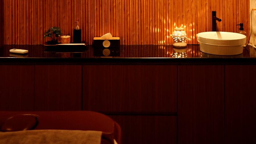 Warmly lit spa interior showing a sleek counter with a sink and wellness products against a wooden wall at Hotel Hukam's Lalit Mahal.