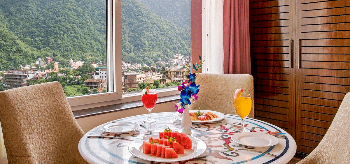 A beautifully set dining table in the suite served with fruits and juice at Regenta Inn DLS.