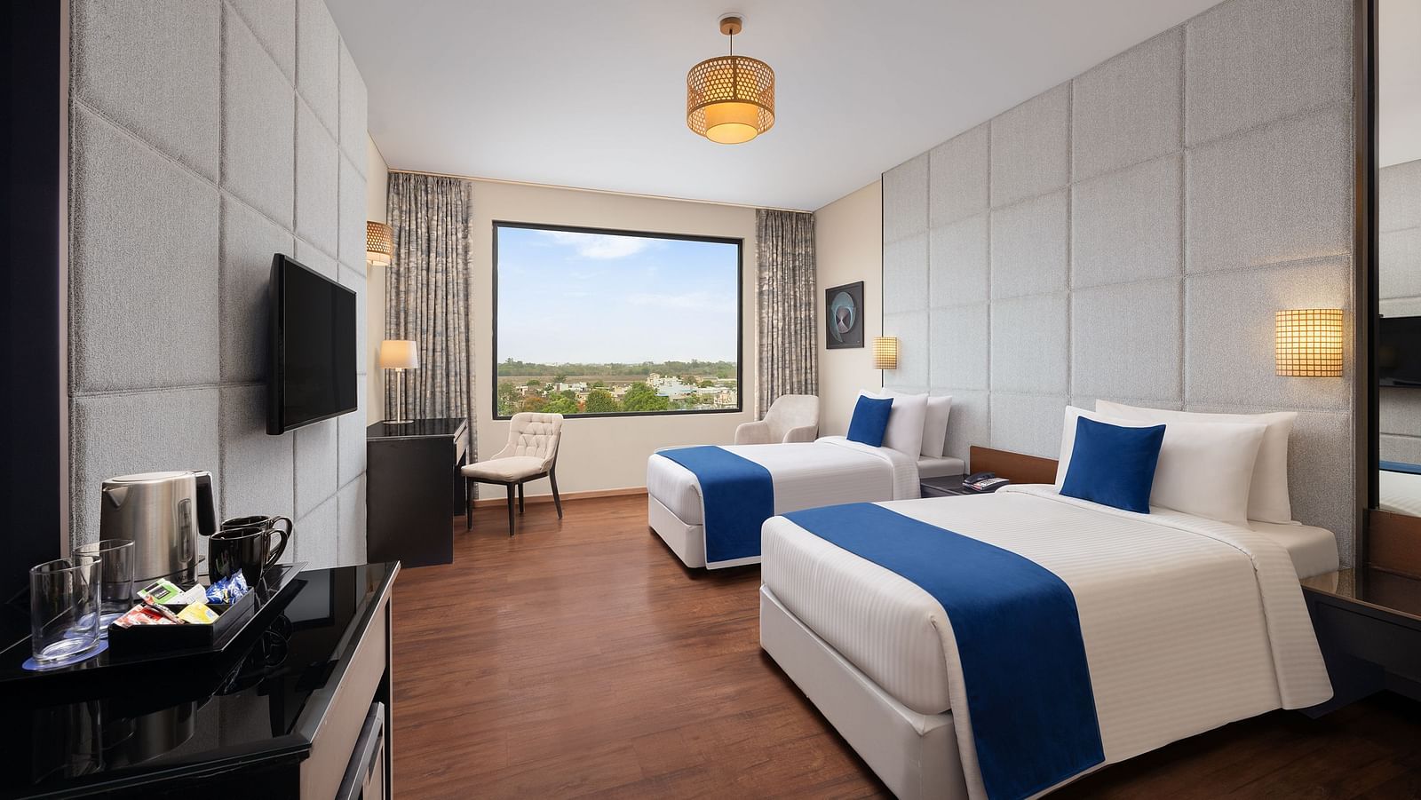 Deluxe Twin Room at Essentia Luxury Hotel, Indore with twin beds, a television and a work desk and chair