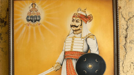 Portrait of Maharana Pratap displayed at the Maharana Pratap Memorial in Udaipur, showing the warrior holding a sword and shield with an illustration of Shree Eklingnathji above and an information plaque below.