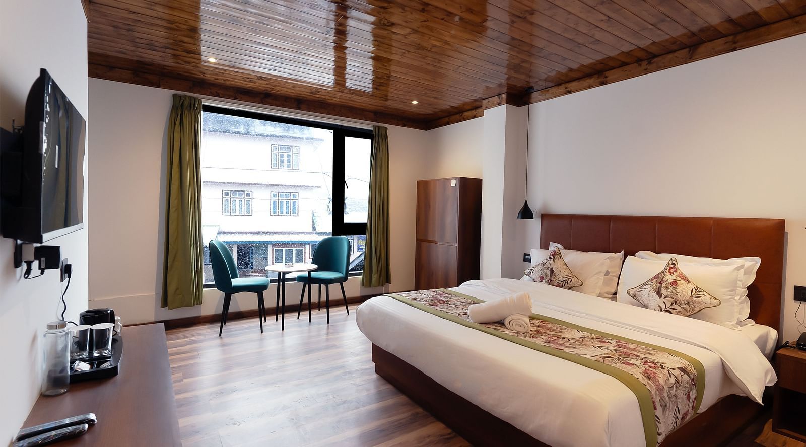 a side view of the premium room with a large bed, a TV and a balcony at Mystique Valley Resort 
