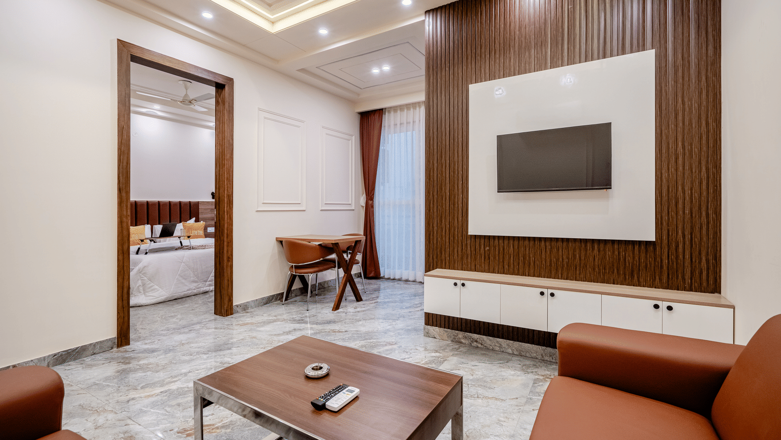 A modern living room featuring brown leather sofas, a central coffee table, and a large wall-mounted wooden television panel.