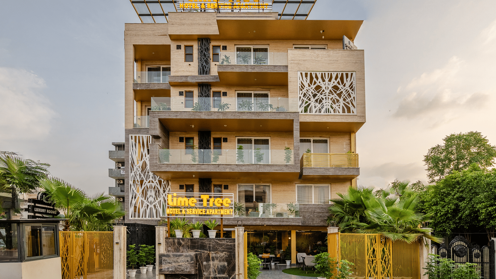 Multiple storey facade of Lime Tree Hotel Near Medanta-The Medicity, Gurgaon featuring an entrance with lawn leading to a building with balconies in each floor attached to the rooms