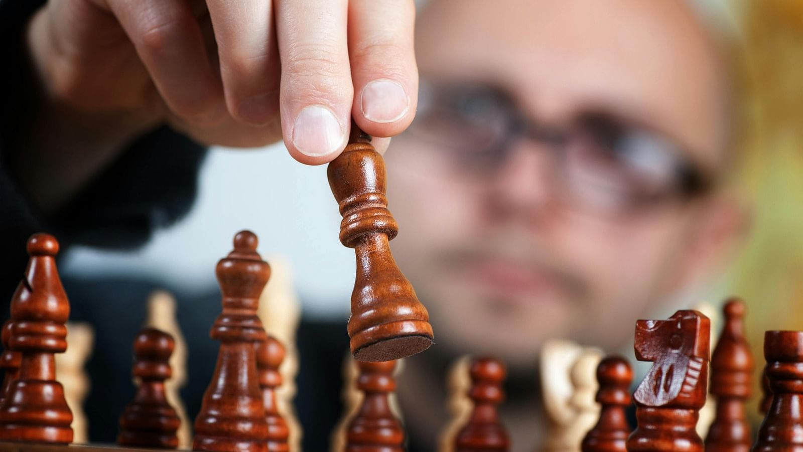 A person playing chess, moving a piece on the board.