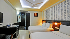 Deluxe Room at Pride Ananya Resort Puri featuring a double bed with a single bed next to it in front of a TV mounted on the wall
