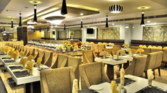 A spacious and elegantly lit restaurant with plush seating, neatly set tables, and a buffet counter – Raj Park Hotel in Alwarpet, Chennai