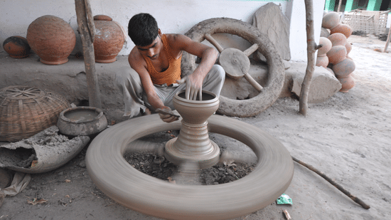 A young boy making pottery using traditional equipment and clay.