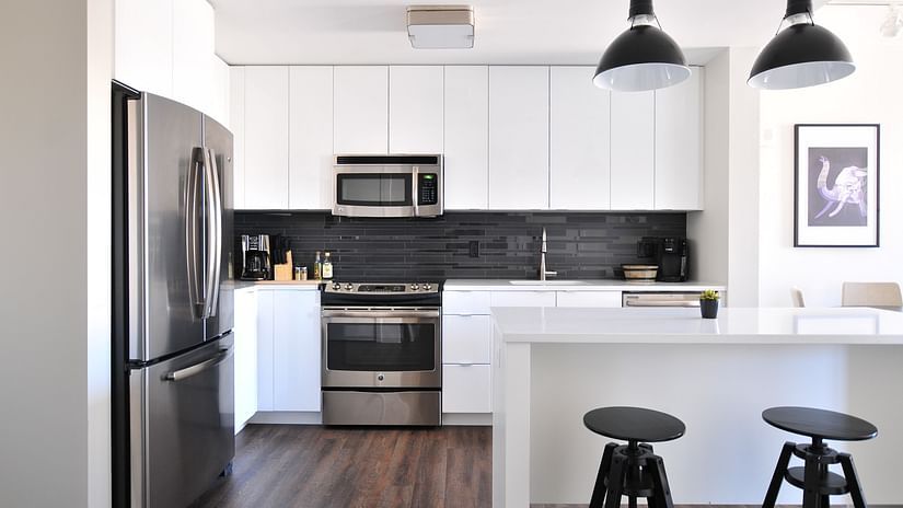 A fully-furnished kitchenette with a refrigerator, chairs, oven, and stove in theory9 service apartment, bandra.