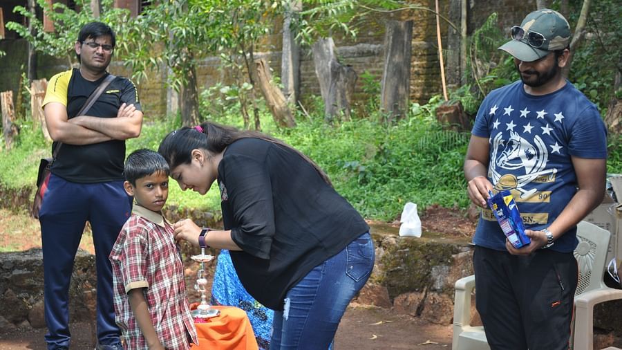 A group of people at Forest Escapes Koyna are engaged in an activity in a lush, green area.