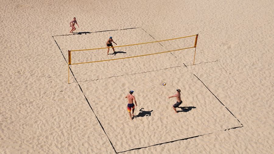 Four people enjoying a lively game of volleyball on the beach.